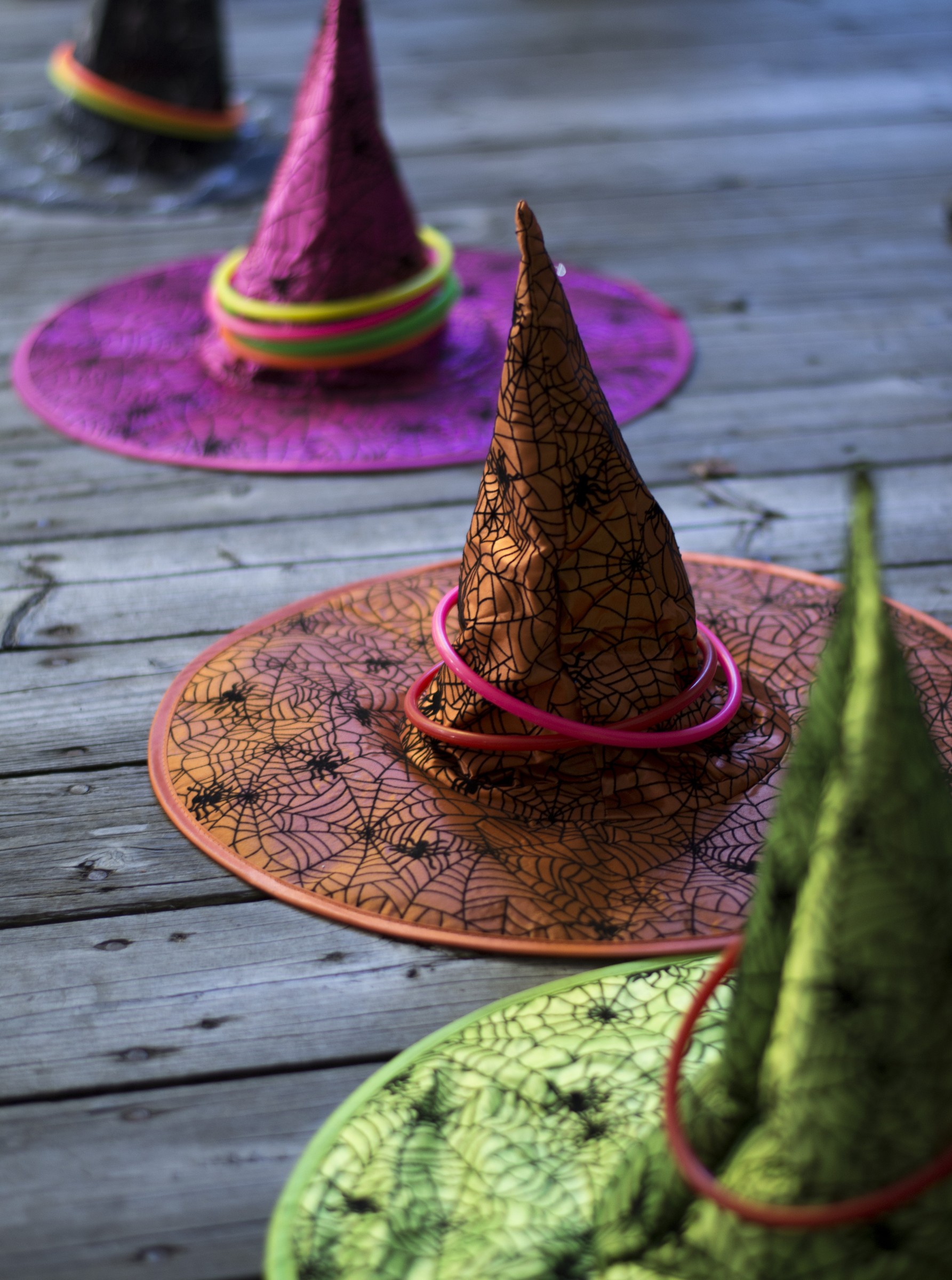 Colorful Halloween witch hats with plastic rings on a wooden deck, a playful daytime craft game at Bear Creek Pumpkin Train.