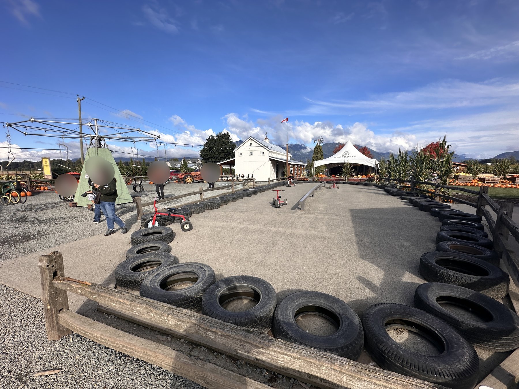 Tire-lined concrete tricycle race track with red trikes, white barn in the background