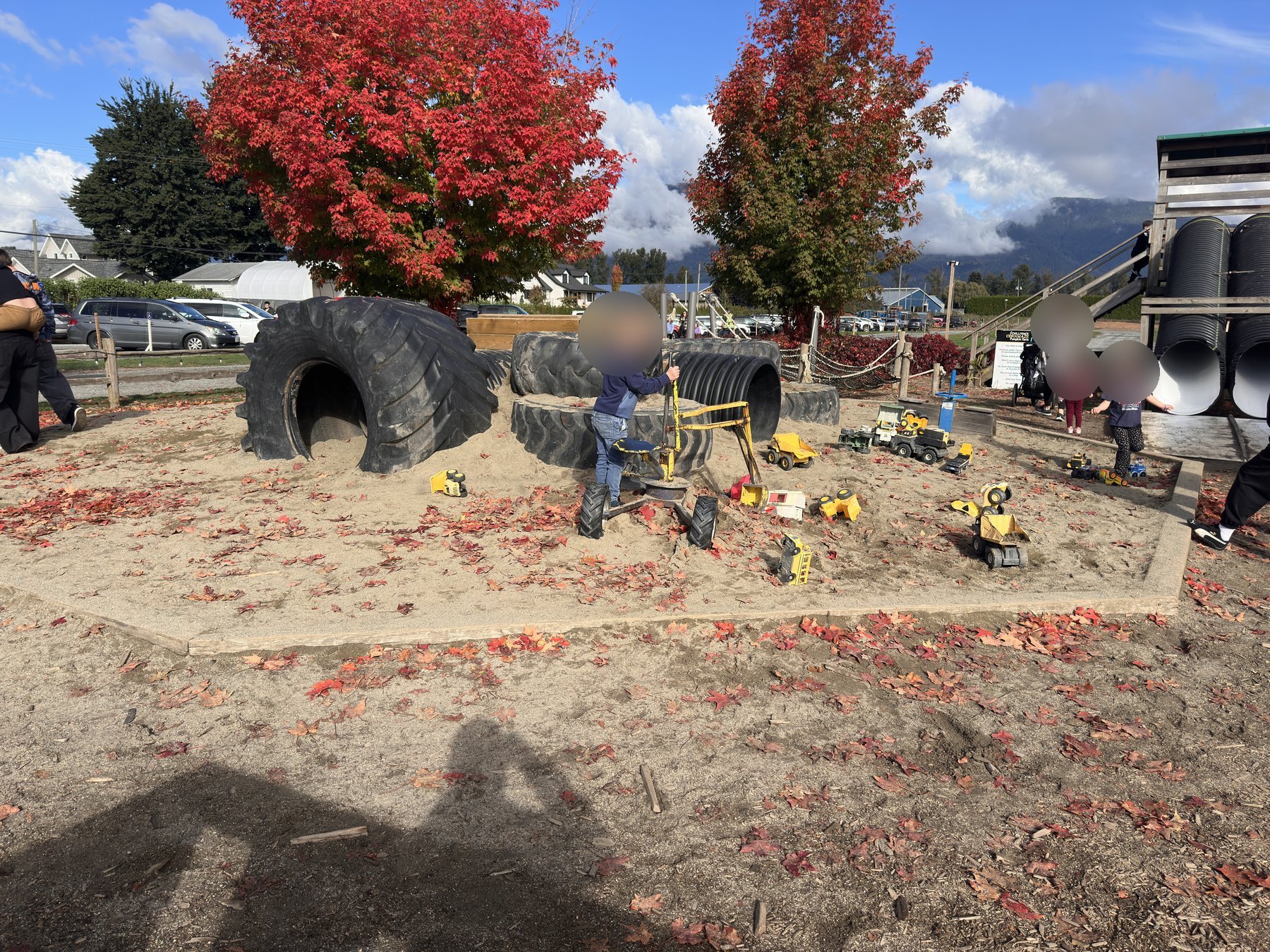Corn-kernel sandbox with giant tractor tires and ride-on toy diggers