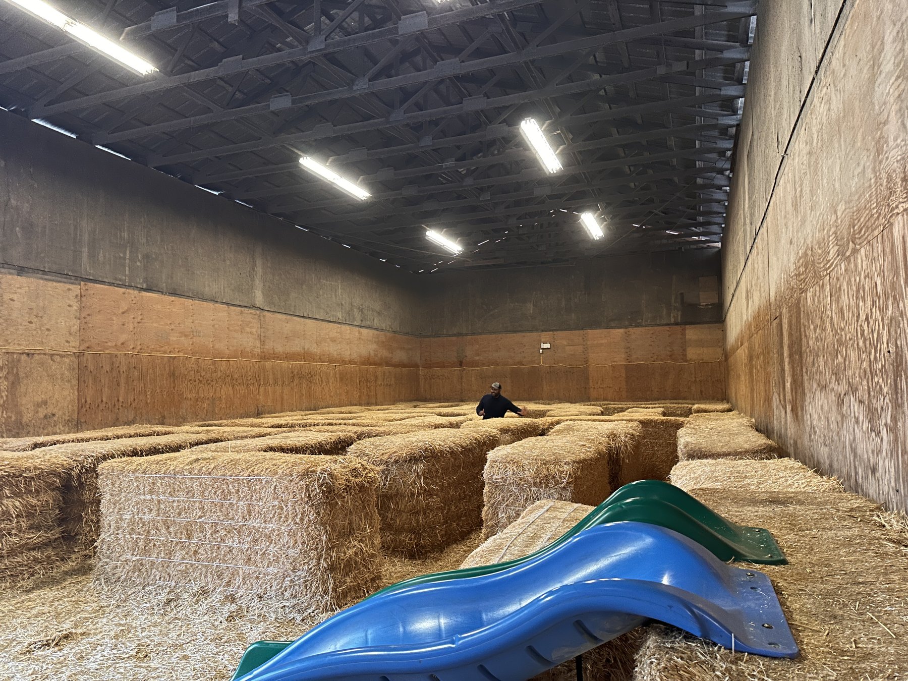 Indoor barn filled with stacked hay bales and a blue plastic slide