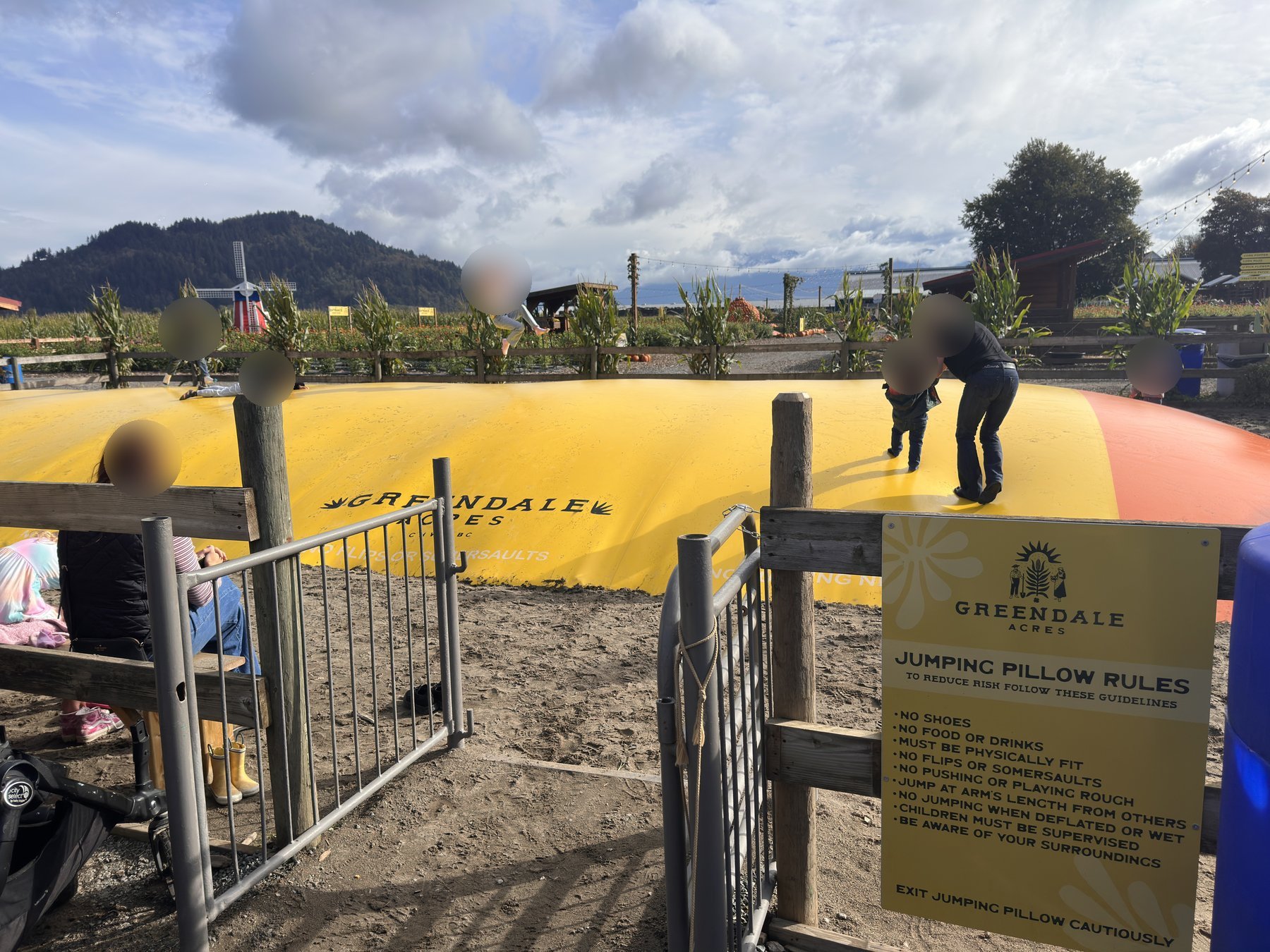 Large yellow and orange jumping pillow with a posted rules sign